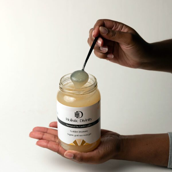 Golden Treasure | Organic Gold Sea Moss Gel | Holistic Divinity | Open jar of gold seamoss held in hand with black spoon coming out