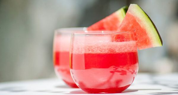 Watermelon juice in two glasses with a triangle of watermelon on each glass for decoration